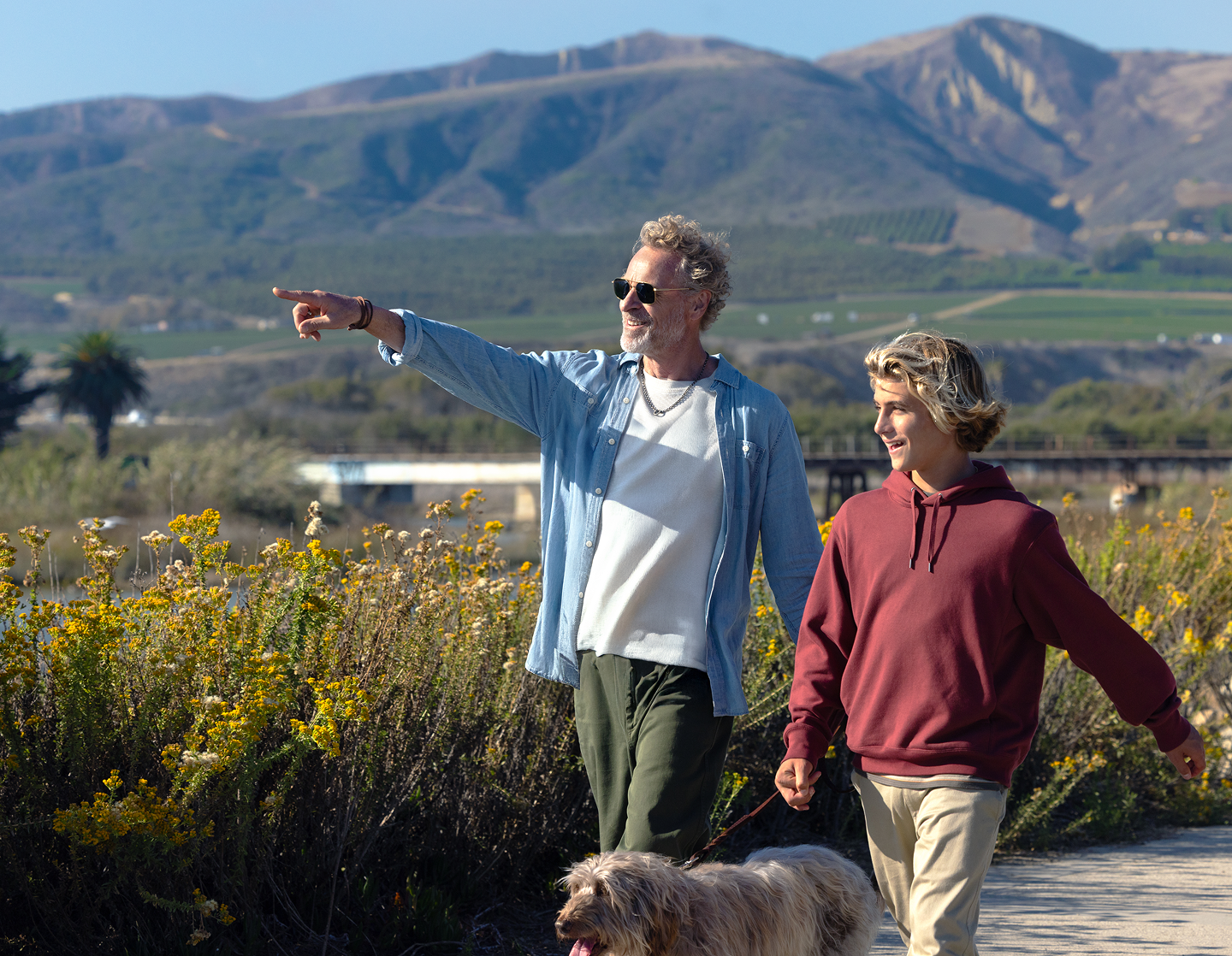Grandfather and grandson walking dog