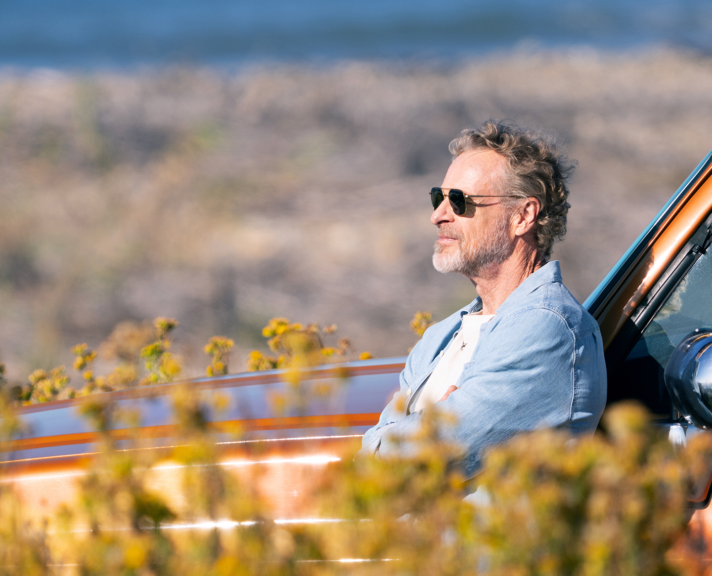 Man leaning on an orange pickup truck