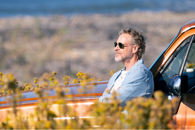 Man leaning on an orange pickup truck
